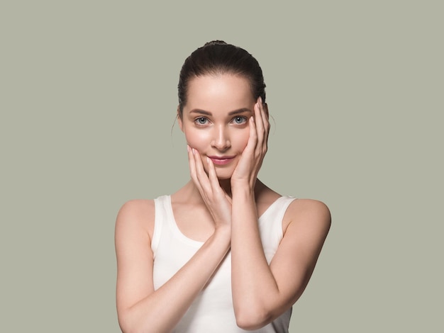 Main de visage de femme en bonne santé de belle peau touchant le fond de couleur de peau fraîche propre et saine. Vert