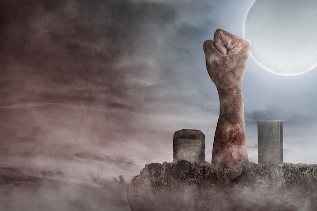 La main de zombie avec des blessures s'élève sur le cimetière avec la pleine lune en arrière-plan concept effrayant d'Halloween