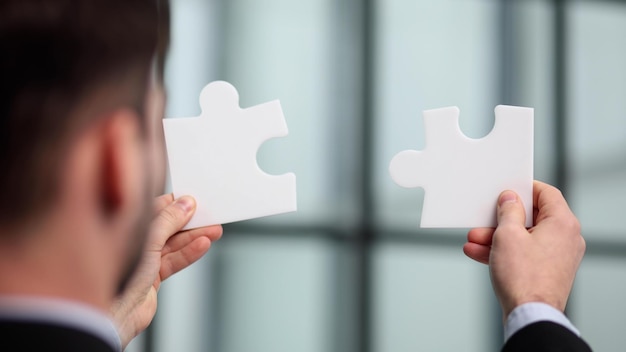 Les mains d'affaires d'un homme d'affaires assemblent des pièces de puzzle