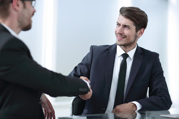 Mains d'affaires se serrant la main assis au Deskphoto avec espace de copie