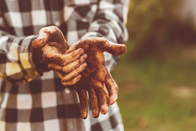 Les mains de l'agriculteur de travail sale dans le sol debout dans le jardin