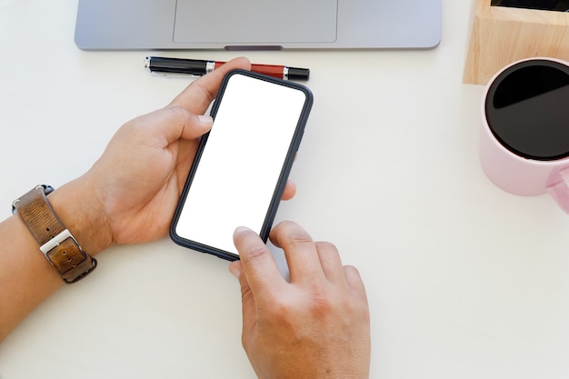 Mains à l&#39;aide de smartphone avec maquette vide écran mobile sur la table de bureau.