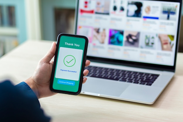 mains à l'aide d'un smartphone pour le paiement en ligne
