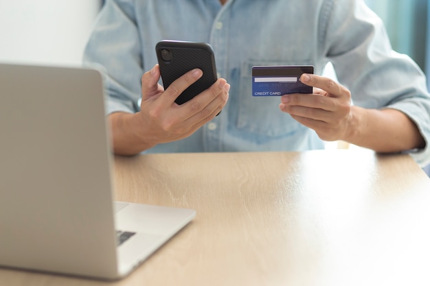 Mains à l'aide d'un téléphone et d'une carte de crédit pour le paiement en ligne