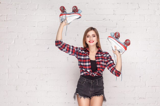 Les mains en l'air! Une femme hipster démontre des quads et un sourire à pleines dents. Prise de vue en studio