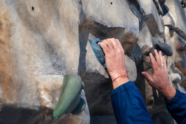 Mains d'alpiniste masculin s'entraînant sur un mur d'escalade