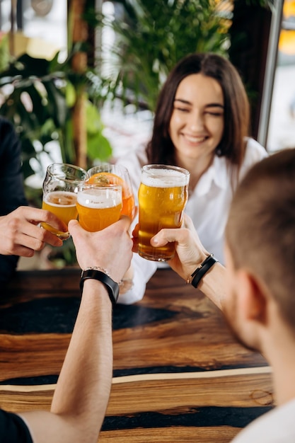 Mains d'amis portant un toast et s'amusant ensemble en buvant de la bière et des cocktails à l'happy hour dans un pub-restaurant Concept de temps de fête de style de vie sociale