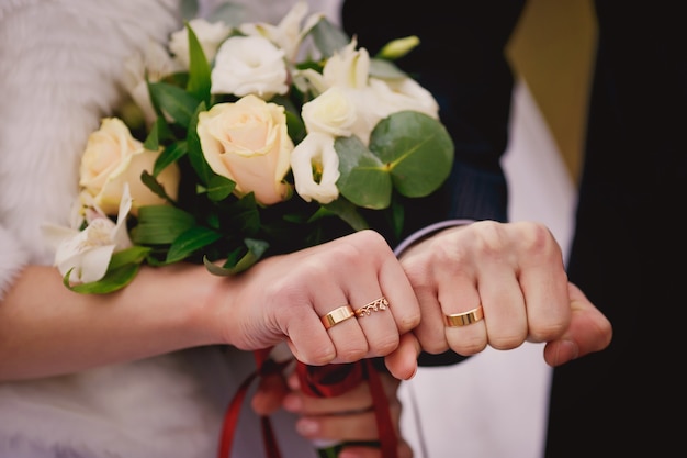 Mains et anneaux sur le bouquet de mariage