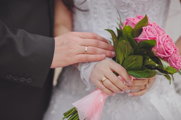 Mains et anneaux sur le bouquet de mariage