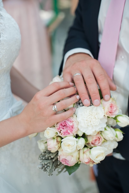 Mains avec anneaux avec un bouquet de mariée