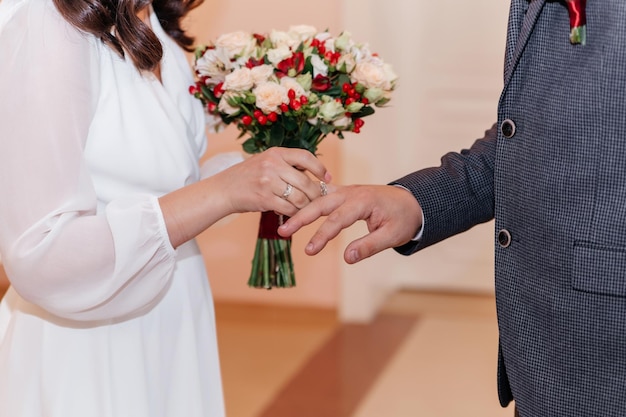 Mains avec des anneaux mariée mettant une bague en or sur le doigt du marié pendant la cérémonie de mariage