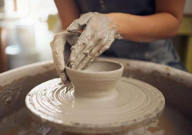 Mains d'argile et de poterie avec une femme designer travaillant dans un studio ou un atelier de design d'art et de céramique Sculpture et roue créatives avec une artiste féminine au travail en tant que potière ou artisane en céramique
