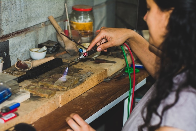 Mains d'un artisan bijoutier tenant un chalumeau. Bijoux d'atelier d'orfèvrerie et articles à valeur de travail.