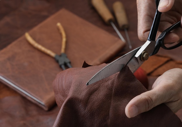 Les mains d'un artisan coupent le cuir