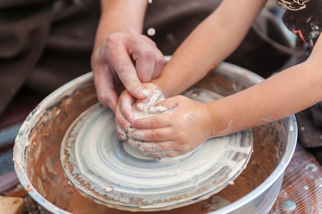 Des mains artisanales fabriquent de l'argile Le maître apprend à l'élève à fabriquer un pichet sur un tour de potier