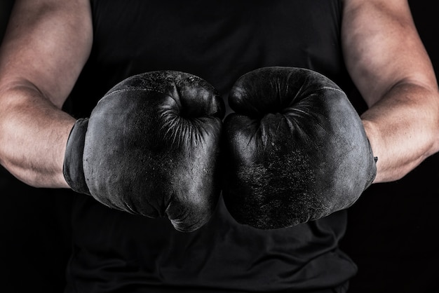 Mains d&#39;un athlète en noir vieux sport gants de boxe