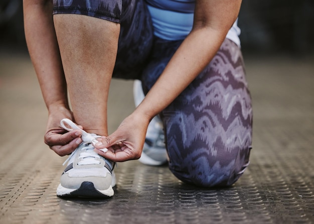 Mains attacher les chaussures et le fitness dans la salle de gym pour commencer l'entraînement ou l'exercice pour le bien-être Athlète sportif et femme attachant des baskets ou des lacets de chaussures pour se préparer à l'exercice ou à la course pour la santé