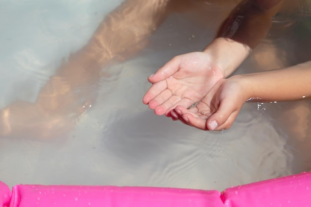 Mains de bébé dans l'eau de la piscine gonflable