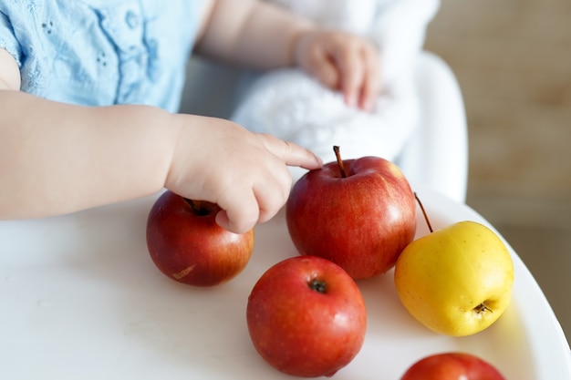 mains de bébé avec des pommes rouges et jaunes