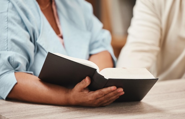 Mains bible et livres avec un couple de personnes âgées lisant un livre ensemble dans leur maison pendant la retraite Foi ou croyance de Jésus avec un homme et une femme priant Dieu dans leur maison pour un lien spirituel
