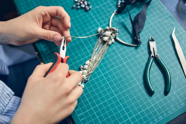 Mains D'un Bijoutier Qualifié En Train De Fabriquer Un Collier à La Mode En Utilisant Une Pince à Bec Rond