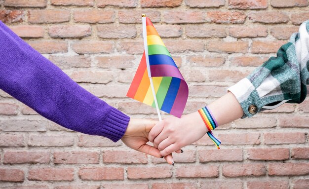 Mains avec brassard arc-en-ciel gay pride et drapeau