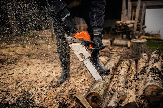 Mains d'un bûcheron coupant des bois avec une tronçonneuse