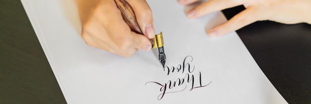 Mains de calligraphe écrit une phrase sur une phrase de papier blanc merci d'inscrire des ornements décorés