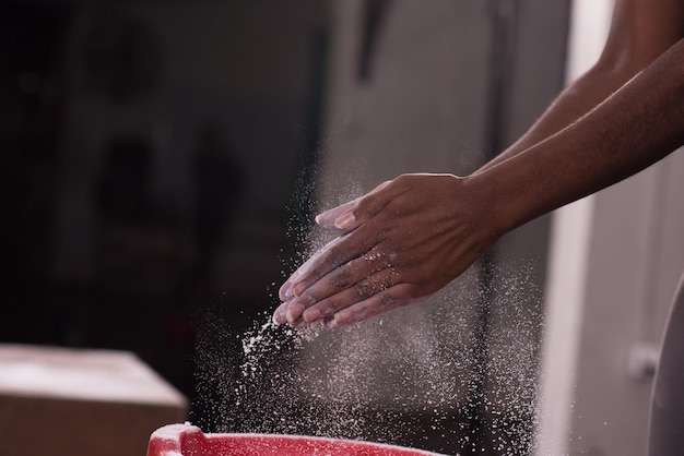 Mains de carbonate de magnésium de craie de gym applaudissant une jeune femme afro-américaine pour l'entraînement d'escalade