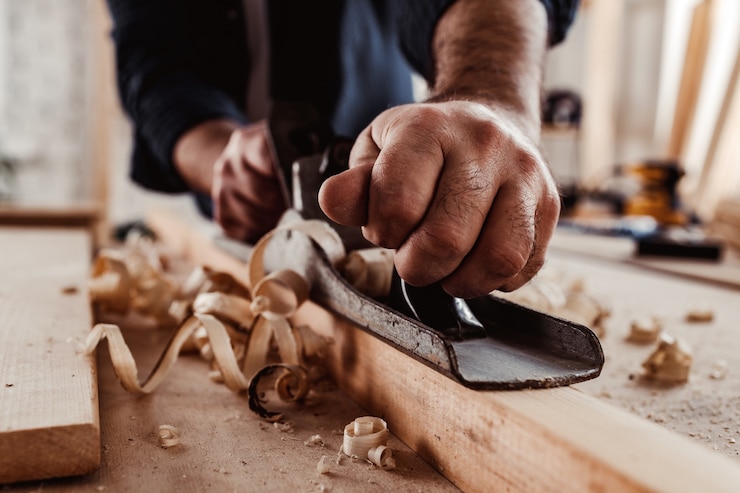 Photo mains de charpentiers rabotant une planche de bois avec un rabot à main