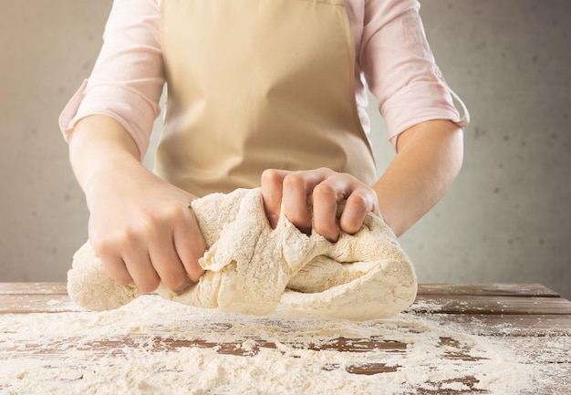 Mains de chef faisant cuire la pâte sur le fond foncé