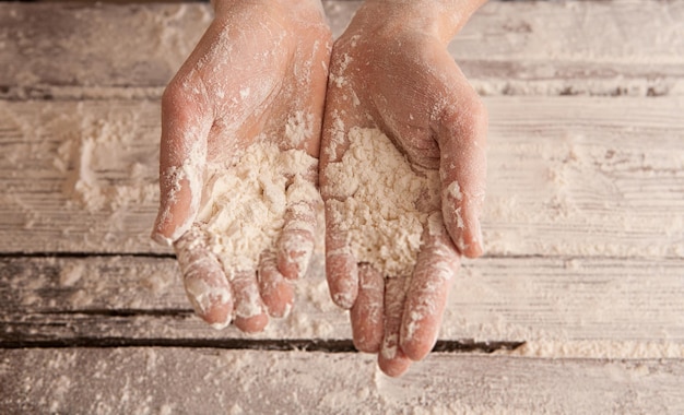 Photo mains de chef avec de la farine sur une table en bois