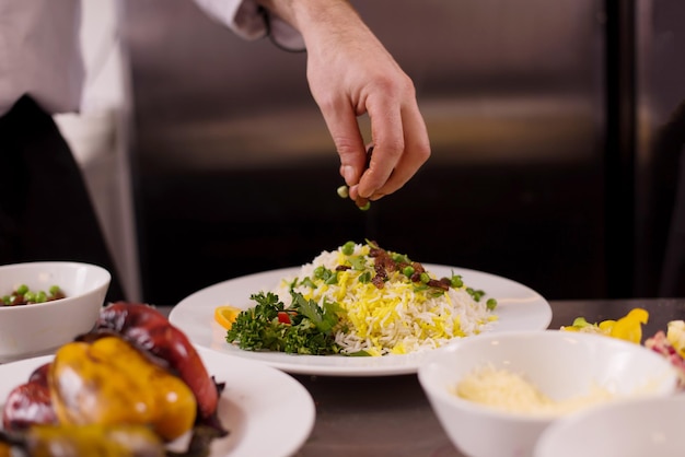 Mains de chef servant un risotto aux légumes dans la cuisine du restaurant