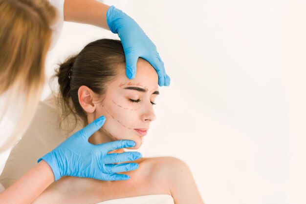 Mains de chirurgien ou d'esthéticienne touchant le visage de la femme.