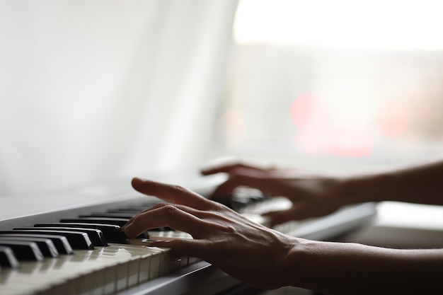 Photo mains sur le clavier d'un piano électronique gris