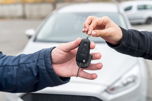 Mains avec clés contre nouvelle voiture close up