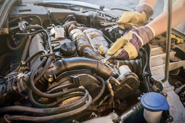 Les mains avec des clés et un moteur de voiture se bouchent. Concept de service de voiture