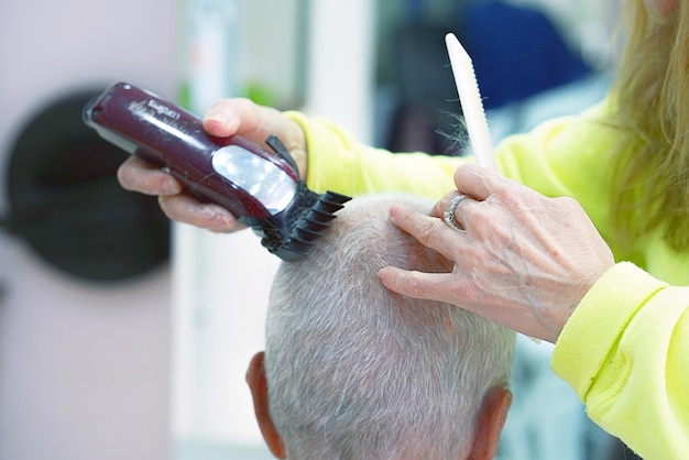 Mains d'un coiffeur de femme âgée coupant un vieil homme