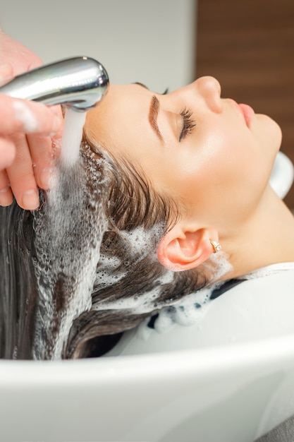 Mains de coiffeur lavant les cheveux de femme