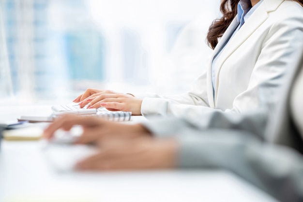 Mains de cols blancs femme tapant sur des claviers d'ordinateur travaillant au bureau