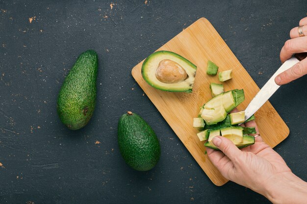 Mains coupant l'avocat sur une planche à découper