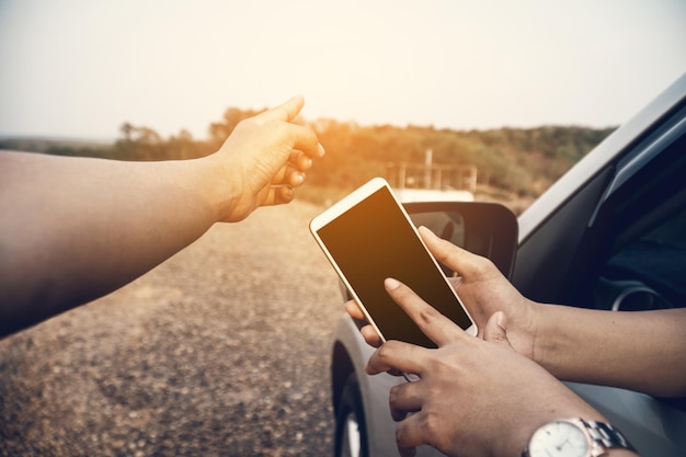 Photo des mains coupées à l'aide d'un téléphone portable tandis qu'une femme pointe vers le ciel