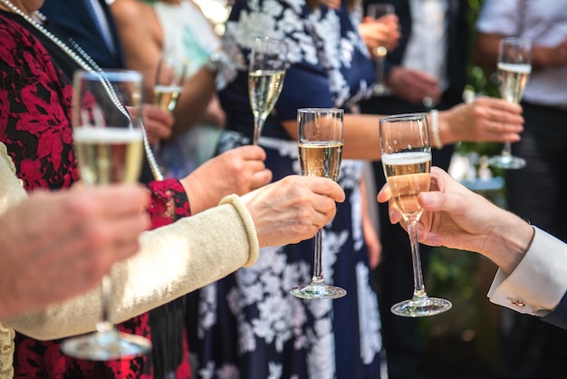 Des mains coupées d'amis en train de faire un toast à des flûtes de champagne lors d'une fête.