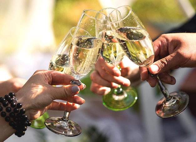 Des mains coupées d'amis en train de faire un toast à des flûtes de champagne lors d'une fête.