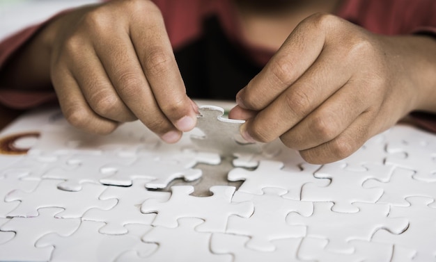 Photo des mains coupées arrangent des pièces de puzzle.