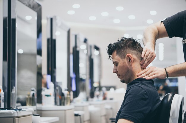 Photo des mains coupées d'un barbier donnant un massage à un client au salon