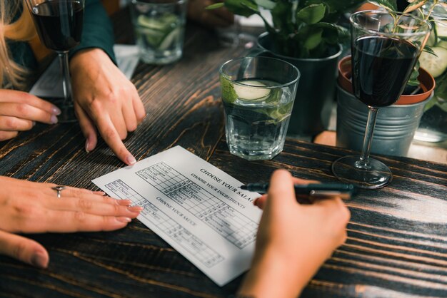 Photo des mains coupées écrivant sur du papier à la table dans un restaurant.