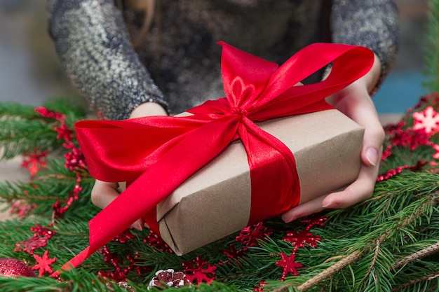 Des mains coupées d'une femme avec un cadeau de Noël sur la table