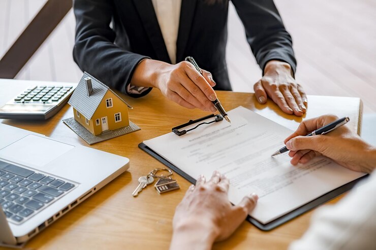 Photo des mains coupées d'une femme signant un document avec un agent immobilier féminin au bureau du bureau