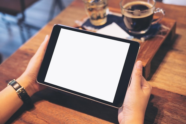 Photo des mains coupées d'une femme utilisant une tablette numérique dans un café